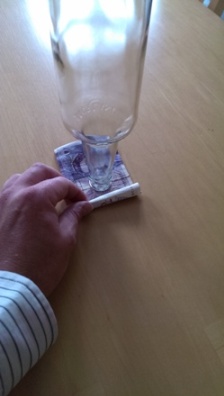SOLUTION: Roll the note slowly inwards, towards the bottle from one or both sides.